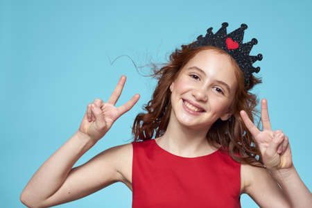 little girl with curly hair with a crown on her head red dress Smile blue backgroundの写真素材