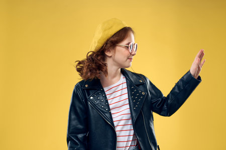 Fashionable girl in a yellow hat glasses clothes studio yellow backgroundの写真素材