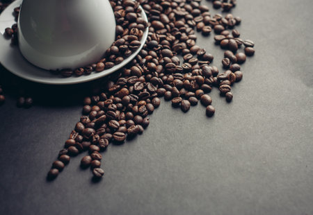 white cup and saucer and large coffee beans on a dark background macro photographyの写真素材