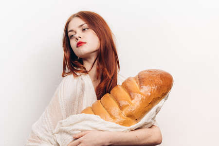 happy red-haired woman with loaf in hands on light background cropped viewの写真素材