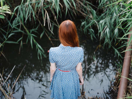 Woman outdoors near green grass and a river in the backgroundの写真素材