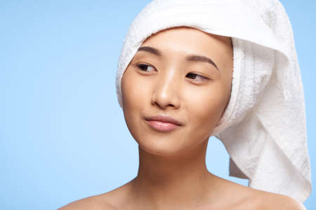 Asian woman naked shoulders and a towel on her head close-upの写真素材