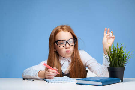 schoolgirl with glasses sitting at the table and doing lessons lifestyle trainingの写真素材
