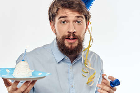 A man with a cake plate and in a blue shirt on a light background birthday party corporate capの写真素材