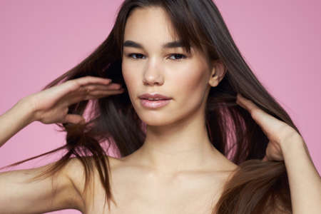 Woman with bare shoulders hair care makeup clean skin pink backgroundの写真素材
