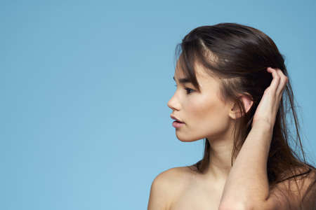 Woman with naked shoulders long hair cosmetics attractive look blue backgroundの写真素材