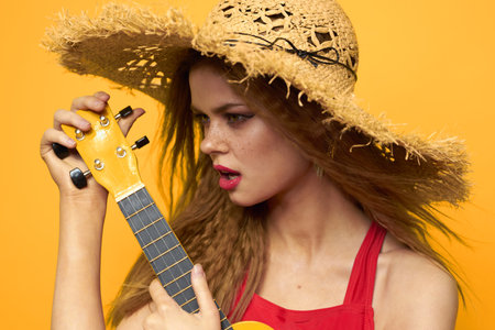 woman in red hat ukulele in hands lifestyle summer red t shirt yellow backgroundの写真素材