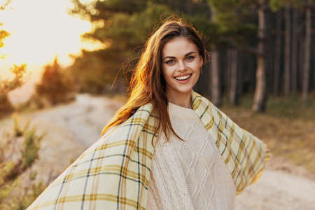 Happy woman with a checkered plaid laughs near the path and coniferous treesの写真素材