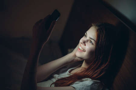 woman with phone in hand bed addiction rest technology
