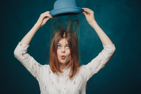 emotional woman in blue hat gesturing with hands red hair blonde sweaterの写真素材