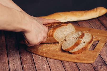slicing a fresh loaf on a cutting board kitchen mealの写真素材