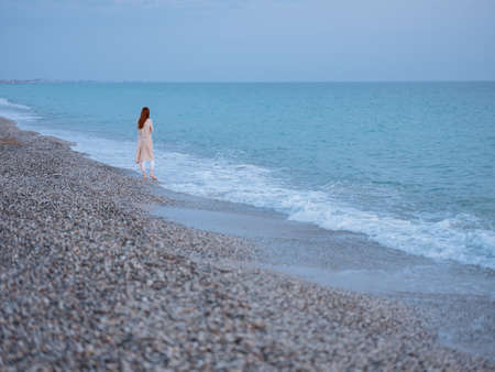 Woman in a sweater by the ocean and blue sky with clear waterの写真素材