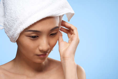 woman with bare shoulders clean skin towel on head blue backgroundの写真素材
