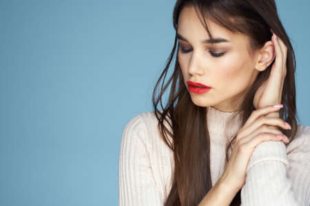 Brunette in white sweater red lips charm cropped view blue backgroundの写真素材