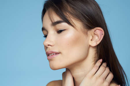 pretty brunette naked shoulders long hair skin care blue backgroundの写真素材