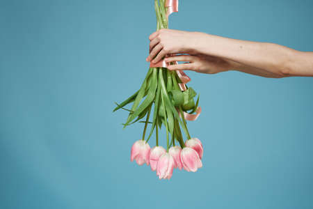 Bouquet in woman hands with gift holiday Valentine Day blue backgroundの写真素材