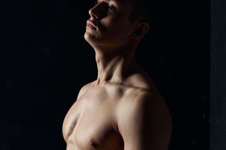 portrait of an athlete with a naked torso on a black background side view Copy Space