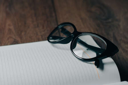 glasses and notebook on wooden table education school office businessの写真素材