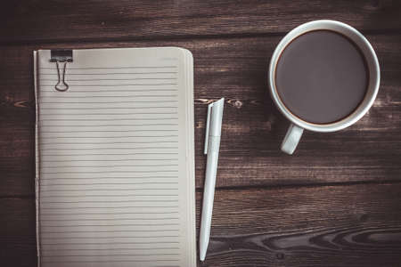 notepad pen and coffee cup on wooden table top viewの写真素材