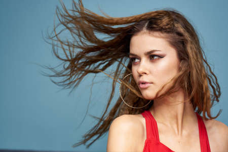 Beautiful woman with wavy hair bright makeup red t shirt lifestyle blue background modelの写真素材