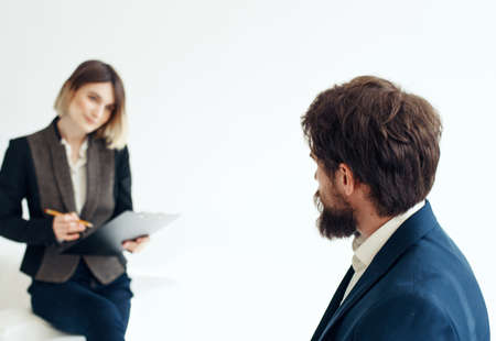 Business woman in a classic suit and a man in a jacket on a light background opposite each other
