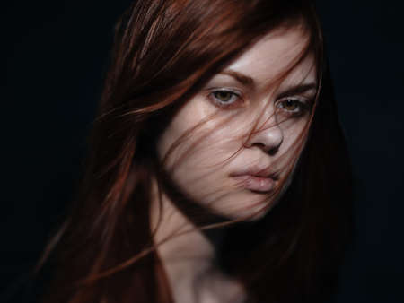 Romantic woman with red hair on a dark background model close-up portraitの写真素材