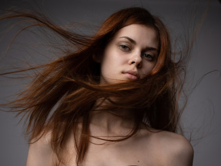 Pretty woman with red hair on a gray background naked shoulders bottom viewの写真素材