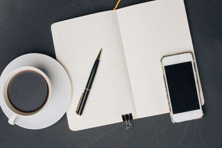 coffee cup on the table notepad with a pen phone technologyの写真素材