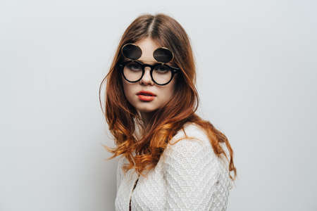Woman in white sweater trendy glasses modern style cropped look and light backgroundの写真素材