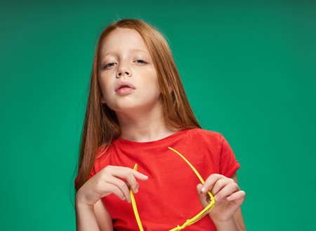 cute girl red hair gestures with hands emotions childhood school Green background