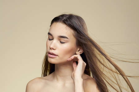 Pretty woman naked shoulders cosmetics clean skin hair care beige backgroundの写真素材