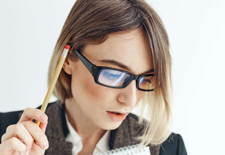 Happy woman with a pencil and glasses on a light background business finance