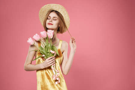 Woman golden dress holiday feminine gift flowers pink backgroundの写真素材