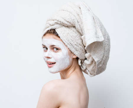 a woman cares for her appearance and a towel on her head and a moisturizer on her faceの写真素材