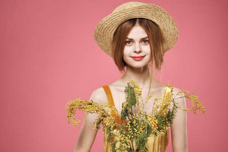 Woman wearing a hat bouquet of mimosa flowers lifestyle pink backgroundの写真素材