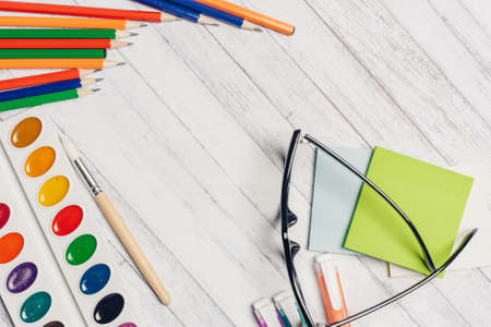 stationery on office desk watercolor paints glasses and colored pencils