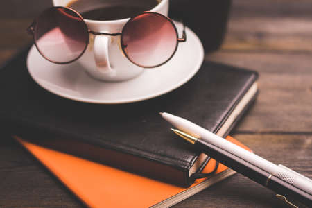 glasses notepads the office handle a cup of coffee saucer wooden tableの写真素材