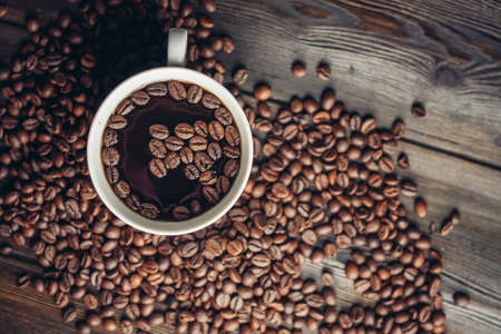 cup with aromatic drink and coffee beans on wooden background top viewの写真素材