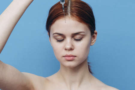 portrait of a woman with a syringe in her hand on a blue background rejuvenation botox injectionの写真素材