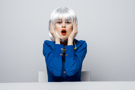 cheerful pretty woman in a white wig sits at the table red lips charmの写真素材