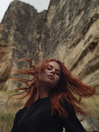 Side view portrait of woman in black dress on nature in mountainsの写真素材