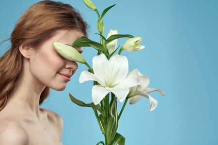 Girl with a bouquet of white flowers on a blue background red hair portrait modelの写真素材