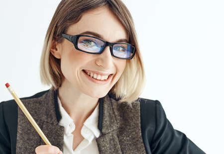 Happy woman with a pencil and glasses on a light background business financeの写真素材