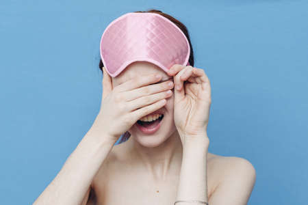 pink sleep mask and energetic woman emotions blue backgroundの写真素材