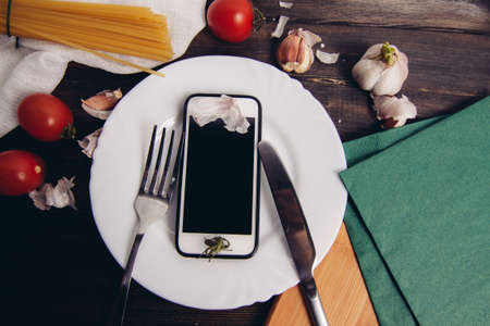 mobile phone plate knife with fork diet food pasta cherry tomatoesの写真素材