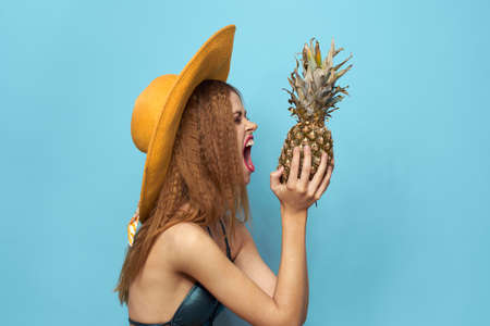 woman in beach hat pineapple holding swimsuit exotic fruits blue background vacation