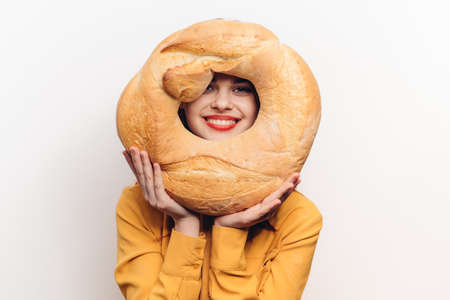 woman with bright makeup holds a round loaf of bread in her hands on a light background Copy Spaceの写真素材