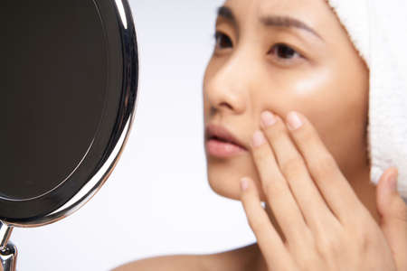 woman looking in the mirror clean skin cosmetology close-upの写真素材