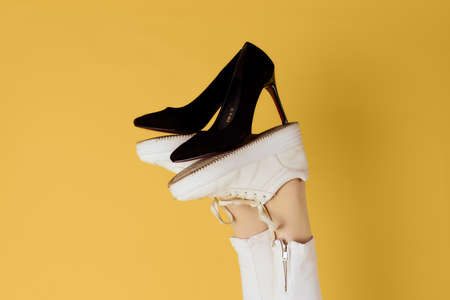 Female feet in sneakers black fashion shoes yellow backgroundの写真素材