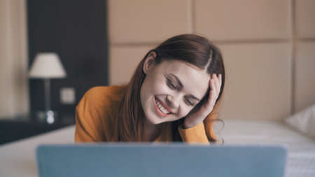 smiling woman lying in front of laptop internet leisure communication technology